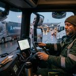 Дальнобойщик в кабине грузовика смотрит на экран с интерфейсом ИИ — страх или возможность