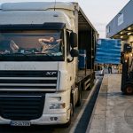 Водитель фуры стоит у рампы склада в Румынии — новый закон запрещает принудительную разгрузку