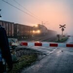 Автомобили перед закрытым железнодорожным переездом с опущенным шлагбаумом и красным светофором